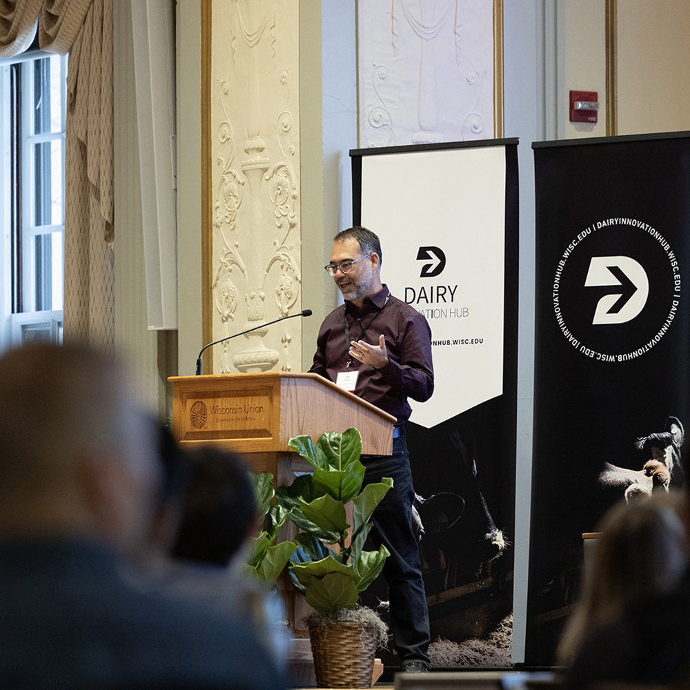 Kyle Cranmer speaks to an audience from behind a podium at the Dairy Symposium.