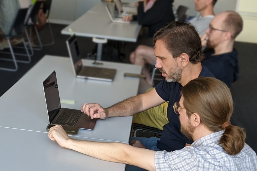 Two men at a workshop looking at a laptop computer.