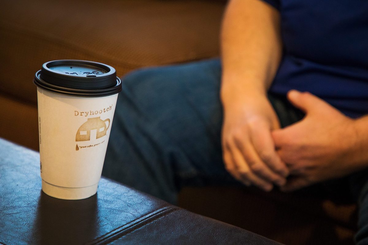 A photo of a person sitting with a coffee cup.