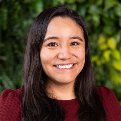 Head shot of Alejandra Quintos. She has long brown hair, and she is wearing a red shirt.
