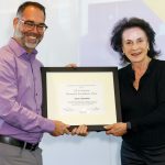 A photo of Kyle Cranmer receiving a framed award from Margot Pritzker
