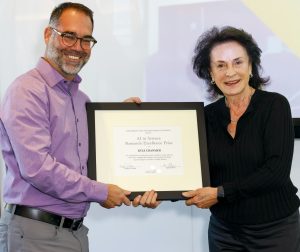 A photo of Kyle Cranmer receiving a framed award from Margot Pritzker