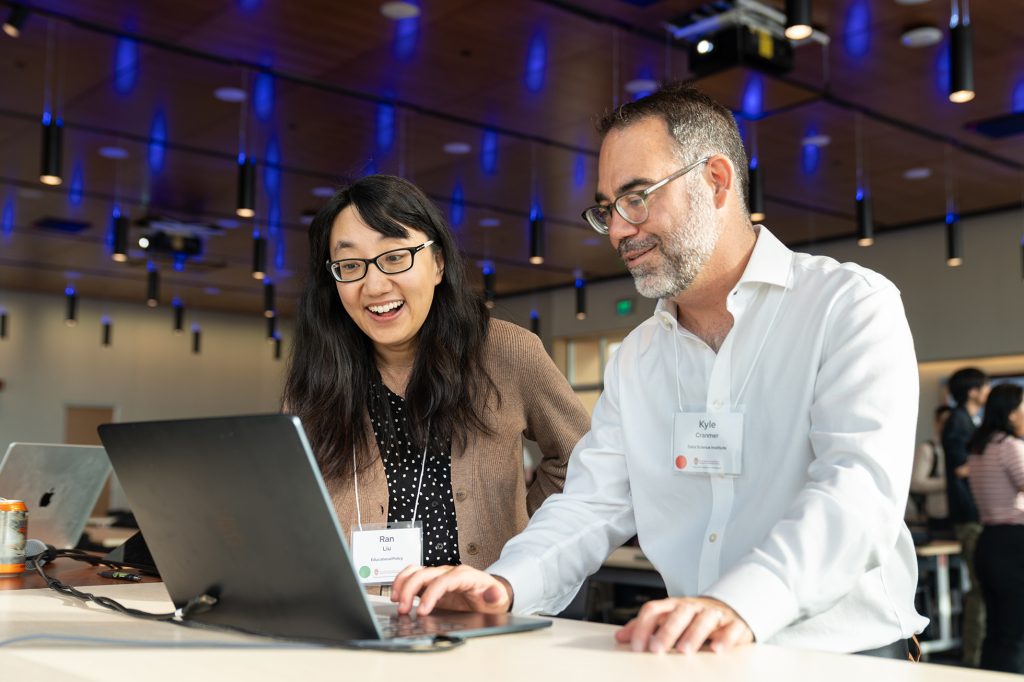 A front view of two faculty members looking at a laptop