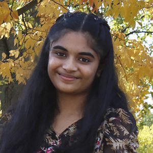 Photo of Diveesha Vanchireddy. She has long dark hair and is wearing a floral dress.